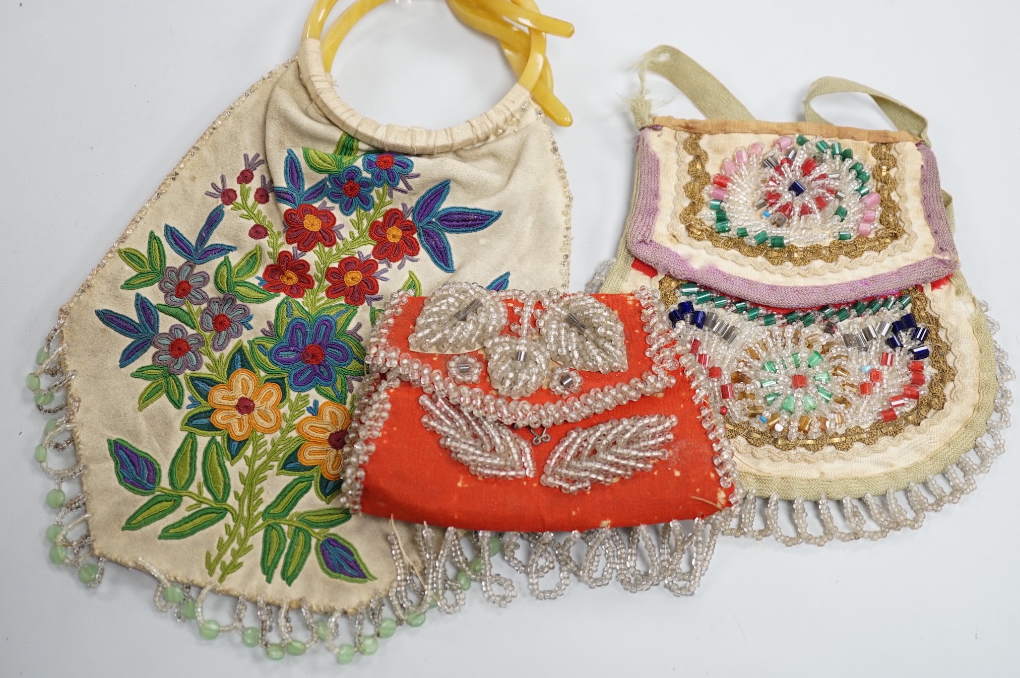 A mid to late 19th century Iroquois, North American/Canadian Indian glass beadwork bag on linen, together with a smaller red wool beaded purse and a 20th century suede embroidered bag with beaded fringe
